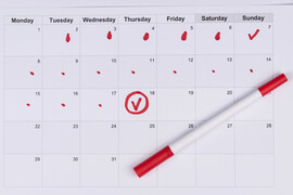 A calendar with red markings on it and a red marker