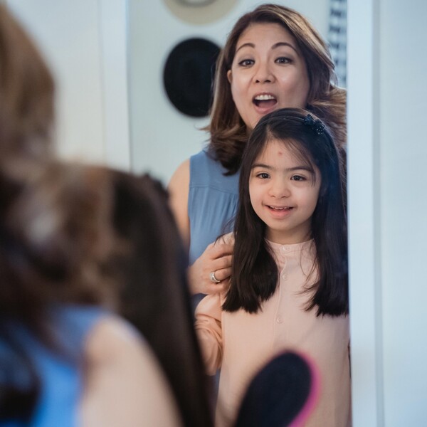 A woman and her daughter look in a mirror together