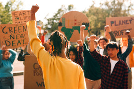 Group of activists protesting for climate action, raising fists and holding signs for environmental justice