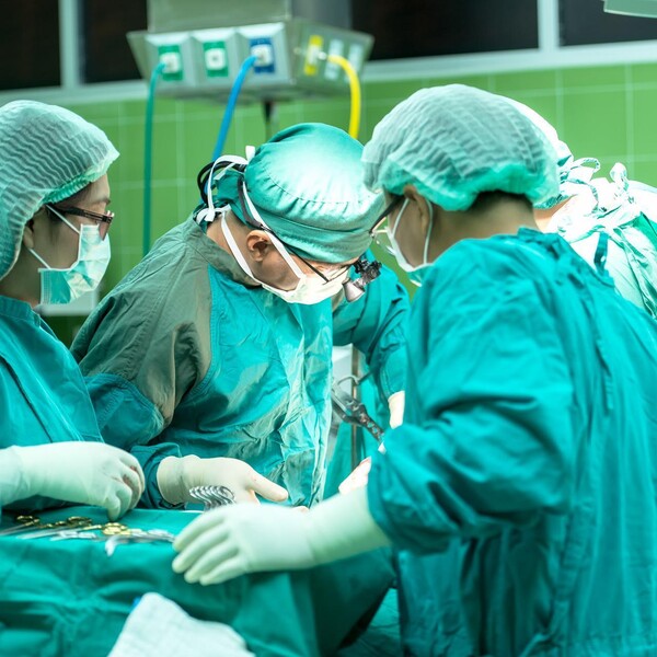 An image of a surgery taking place; surgeons stand around a bed looking on