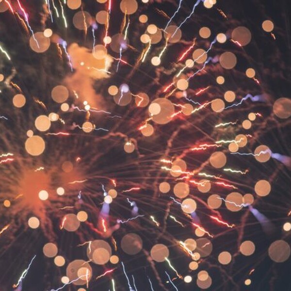 Red and orange fireworks explode against a black background.