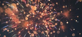 Red and orange fireworks explode against a black background.