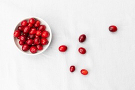 Red cranberries spill out of a small white bowl.