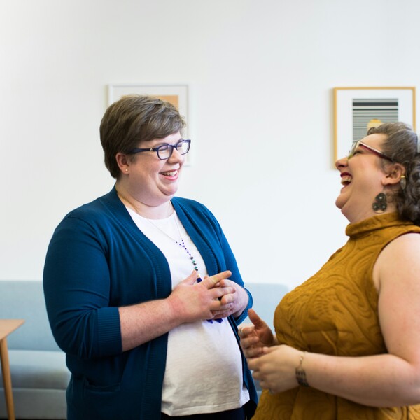 Two white women laughing in an office.