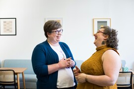 Two white women laughing in an office.