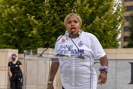 A Black woman wearing a shirt that reads "Bans Off Our Bodies" speaks at a podium.