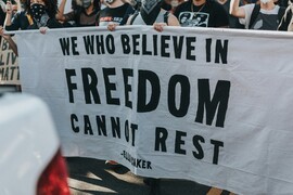A group of people holding a sign that says "we who believe in freedom cannot rest."