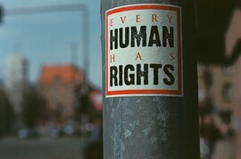 Sticker on pole that reads "Every Human Has Rights."