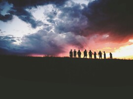 A multicolored sky highlights the silhouettes of a group of people.
