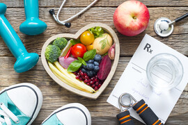 Photo of dumbbells, bowl of fruit and vegetables, shoes, apple, stethoscope, and prescription pad that has "fruit and vegetables" written on it.