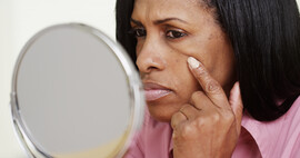 Closeup of black middle aged woman looking into mirror.