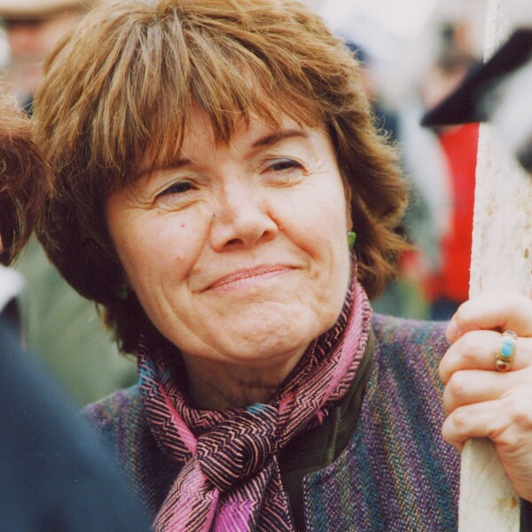 closeup photo of woman with short, straight reddish-brown hair, smiling slightly, with a kind expression, as she looks off to the right