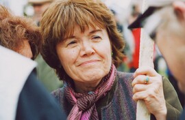 closeup photo of woman with short, straight reddish-brown hair, smiling slightly, with a kind expression, as she looks off to the right